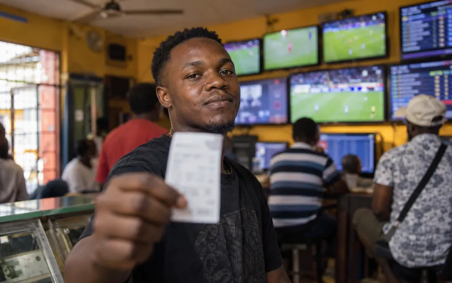 Free bet in Tanzania: a printed bet slip held up in front of a betting shop screen